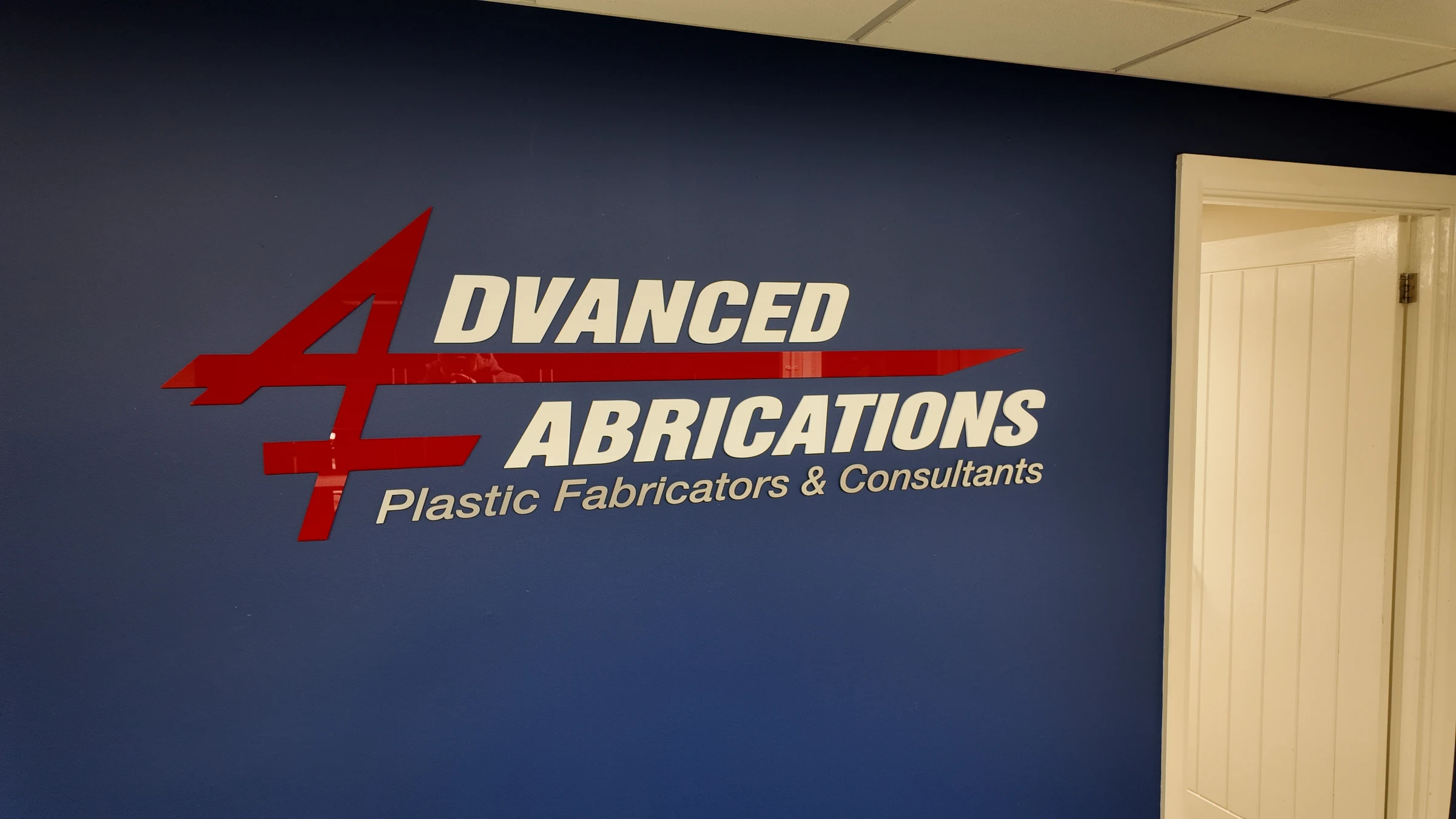 The red and cream Advanced Fabrications logo on the navy reception wall
